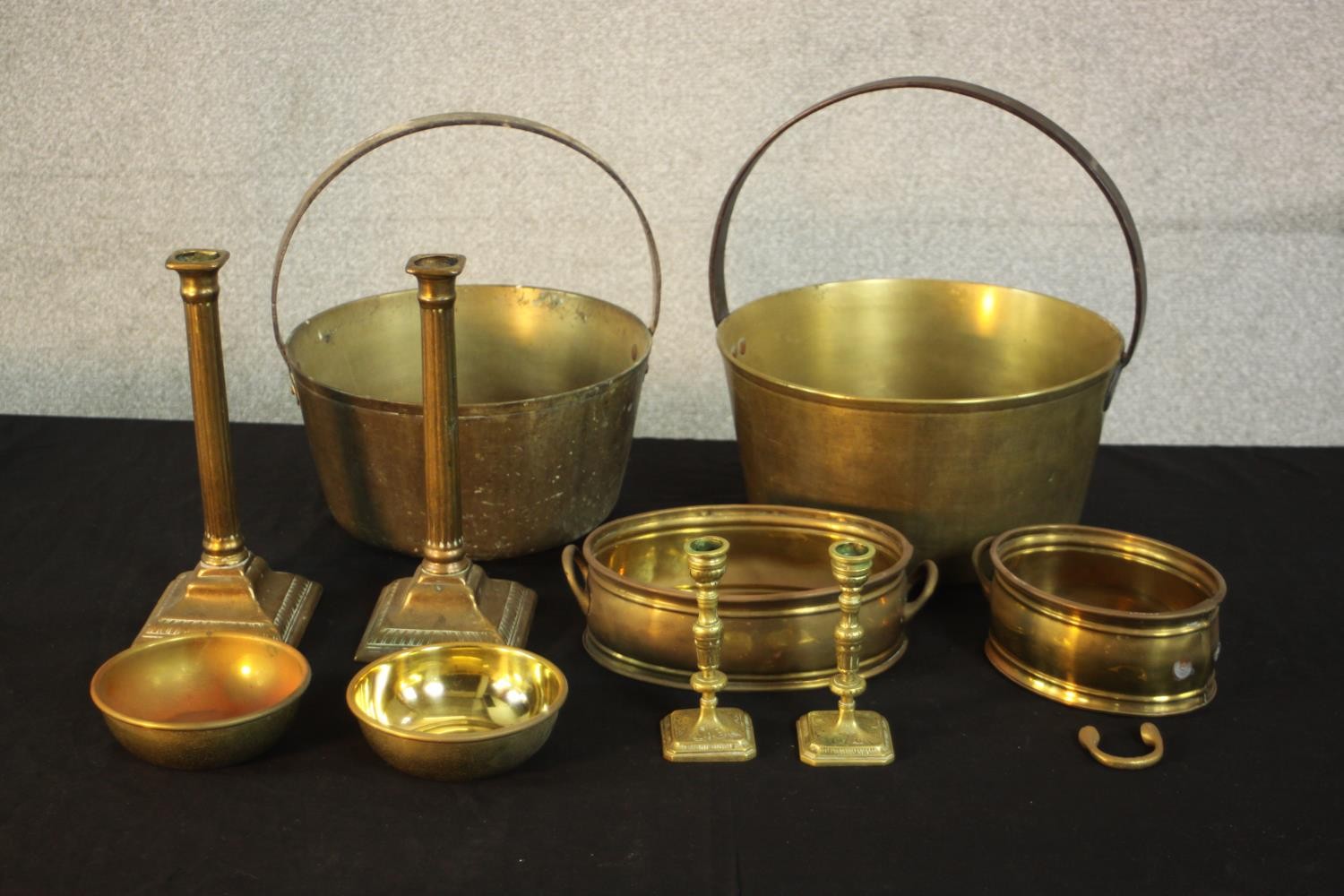 A collection of early 20th century brassware, including two brass preserve pans, two pairs of candle