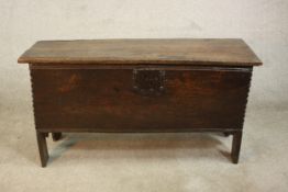 An 18th century oak plank form coffer, with a hinged lid, and an iron lock on shaped end supports.