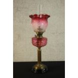 A Victorian paraffin oil lamp, with cranberry coloured reservoir, cranberry tinted acid etched shade