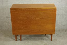 A circa 1960s teak drop leaf dining table of rectangular form with two drop leaves on tapering