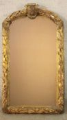 A 19th century gilt framed wall mirror, the rounded top centred by a carved heraldic crest, the