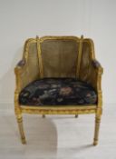 A 19th / early 20th century French style gilded cane work armchair raised on fluted tapering