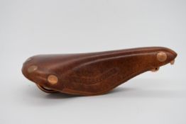 An early 20th century brown bakelite bicycle saddle with impressed marks. H.6.5 W.28 D.17cm