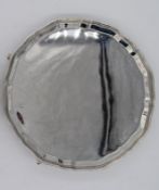 A George V hallmarked silver salver raised with pie crust rim on three outswept supports, John