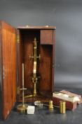 A late 19th / early 20th century boxed brass microscope, complete with various lenses, accessories