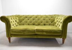 A contemporary button back Chesterfield style two seater settee, with scroll arms raised on turned