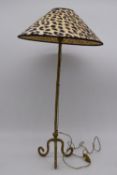 A contemporary brass effect table lamp raised on three scroll feet with leopard print shade. H.66cm