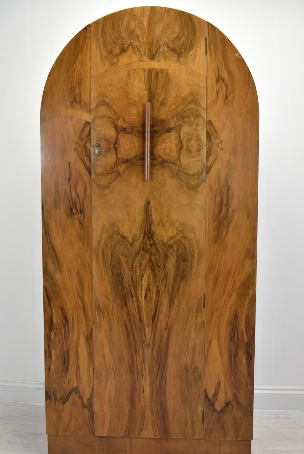 An Art Deco walnut veneered dome topped and twin door wardrobe, opening to reveal mirror, raised