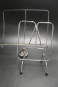A silver plated modernist magazine rack raised on pad feet together with a chrome plated magazine