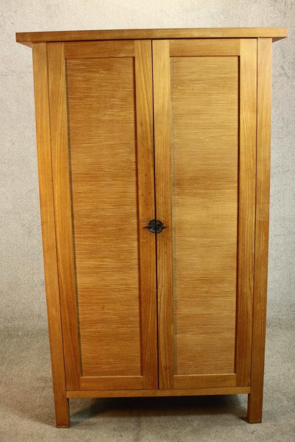 A contemporary hardwood two door floor standing cabinet, enclosing three shelves, on square