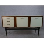 A 1960s white formica Stonehill Furniture sideboard, with a fall front drinks cabinet flanked by