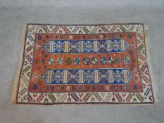 A rust ground hand made Turkish Indigo rug. W.140 D.91cm