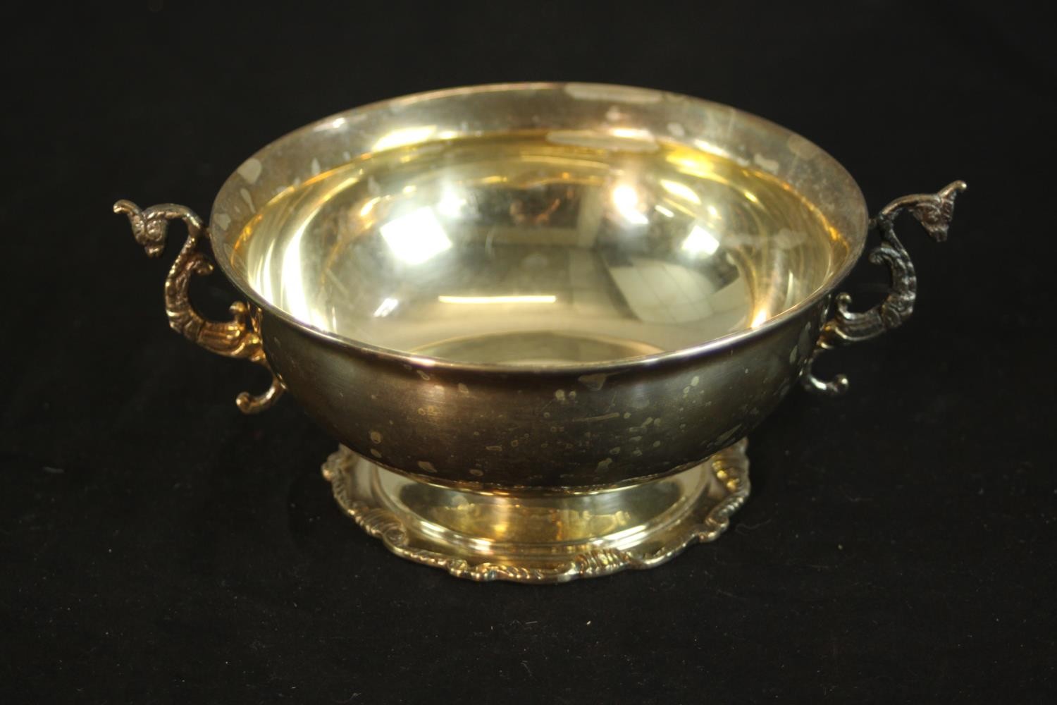A sterling silver Egyptian twin handled porringer with seahorse form handles on a pedestal foot.