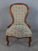 A Victorian walnut framed spoon back nursing chair, upholstered in buttoned patterned fabric, raised