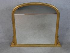 A contemporary Victorian style gilt framed overmantel mirror with a rounded top, flanked by carved