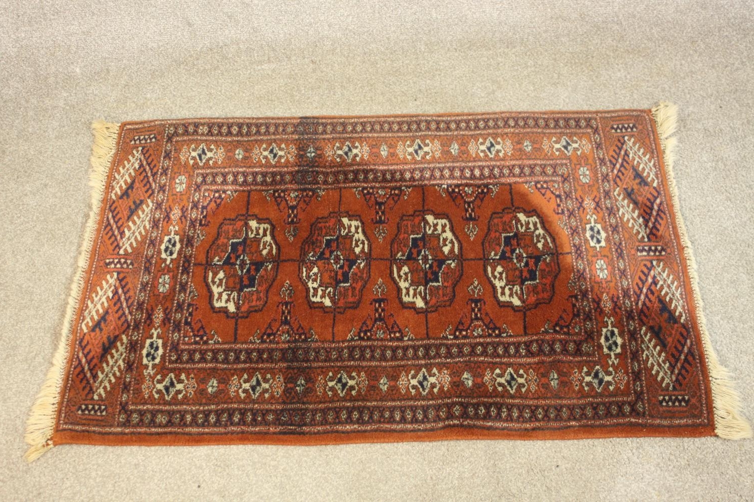 A hand made rust ground Bokara rug. L.92 W.54cm.