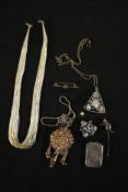 A collection of silver jewellery including a silver and garnet cat stick pin, a multi strand