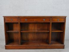 A George III style yew wood open bookcase with three short crossbanded drawers over three shelves,