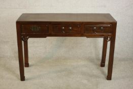 A 20th century Chinese side table of panelled construction with three short drawers over a carved