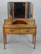 An early 20th century mahogany bow fronted dressing table with triptych mirror above two drawers and