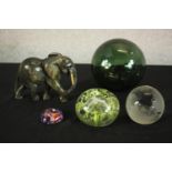 A blown green glass fishing float, three art glass paperweights and a carved soapstone elephant.