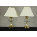 A pair of Victorian brass oil lamps converted to electricity, each with a glass reservoir, on a