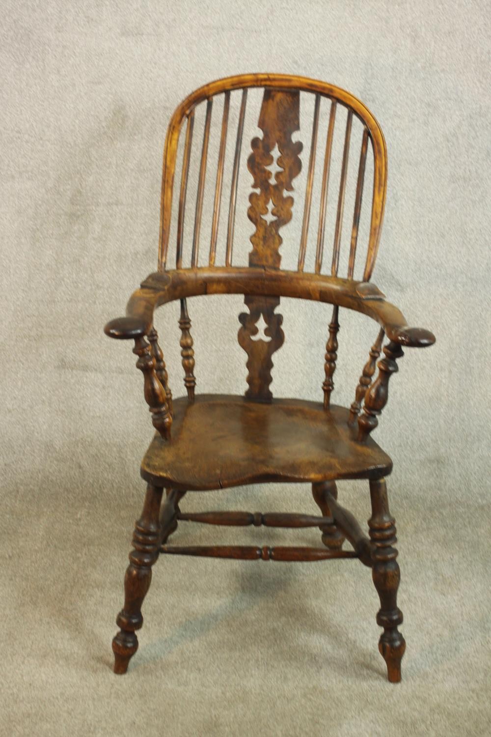 A 19th century Windsor armchair, with a yew hoop back and pierced splat over an elm seat, on