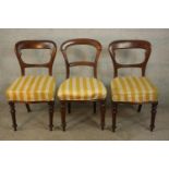 A pair of Victorian walnut dining chairs, upholstered in white and yellow striped fabric, on