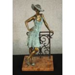 Laszlo Kutas, 1936, patinated bronze of a lady in a hat leaning on a cast iron railing, mounted on a