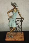 Laszlo Kutas, 1936, patinated bronze of a lady in a hat leaning on a cast iron railing, mounted on a