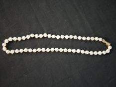 A vintage knotted cultured pearl necklace with ridged 10 carat gold conical design push clasp with