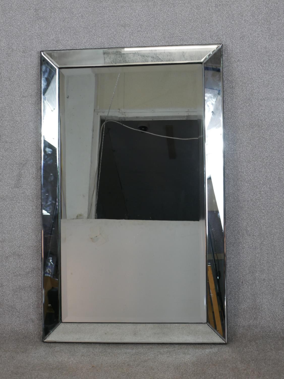 A contemporary rectangular wall mirror with a rectangular bevelled mirror plate in a bevelled mirror