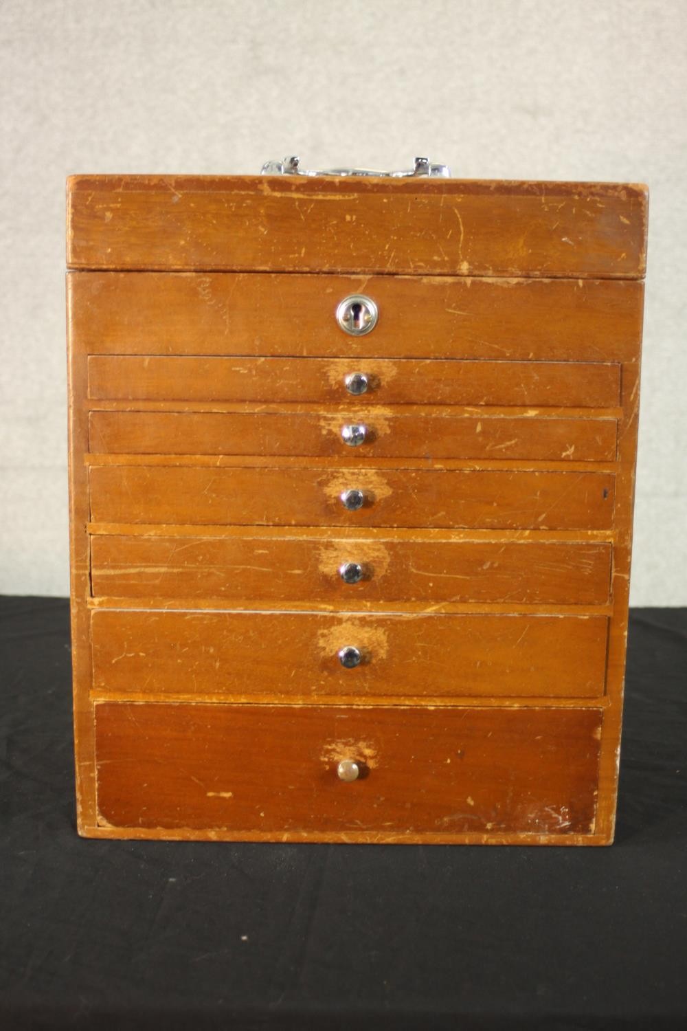 A mid 20th century teak collector's cabinet, with a foldover lid above six graduated fitted