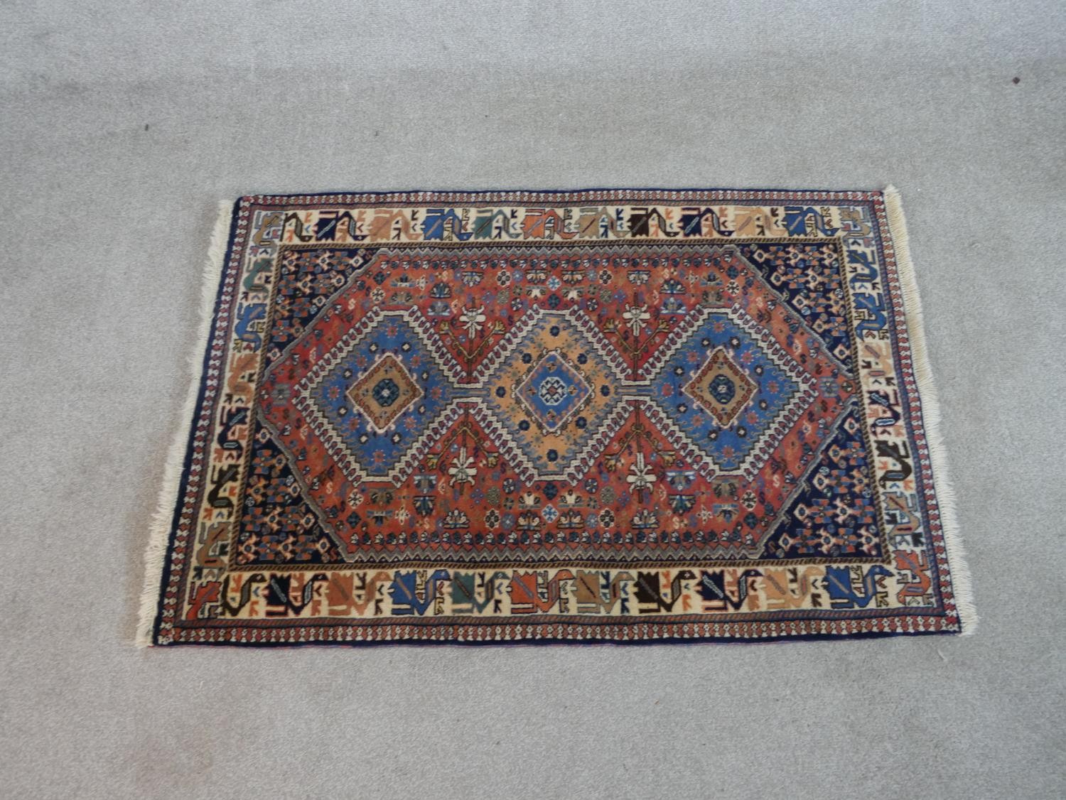 A rust ground hand made Persian Yalameh rug. W.126 D.86cm