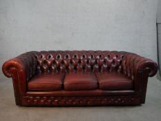 A 20th century oxblood red Chesterfield three seater settee, raised on casters, H.65 W.195 D.67cm