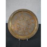 A Middle Eastern circular copper tray, with engraved decoration, with silver mounted vines and