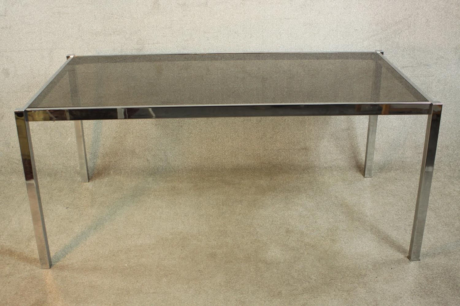 A 1970's dining table with a smoked plate glass top on a square section tubular chrome frame. H.74