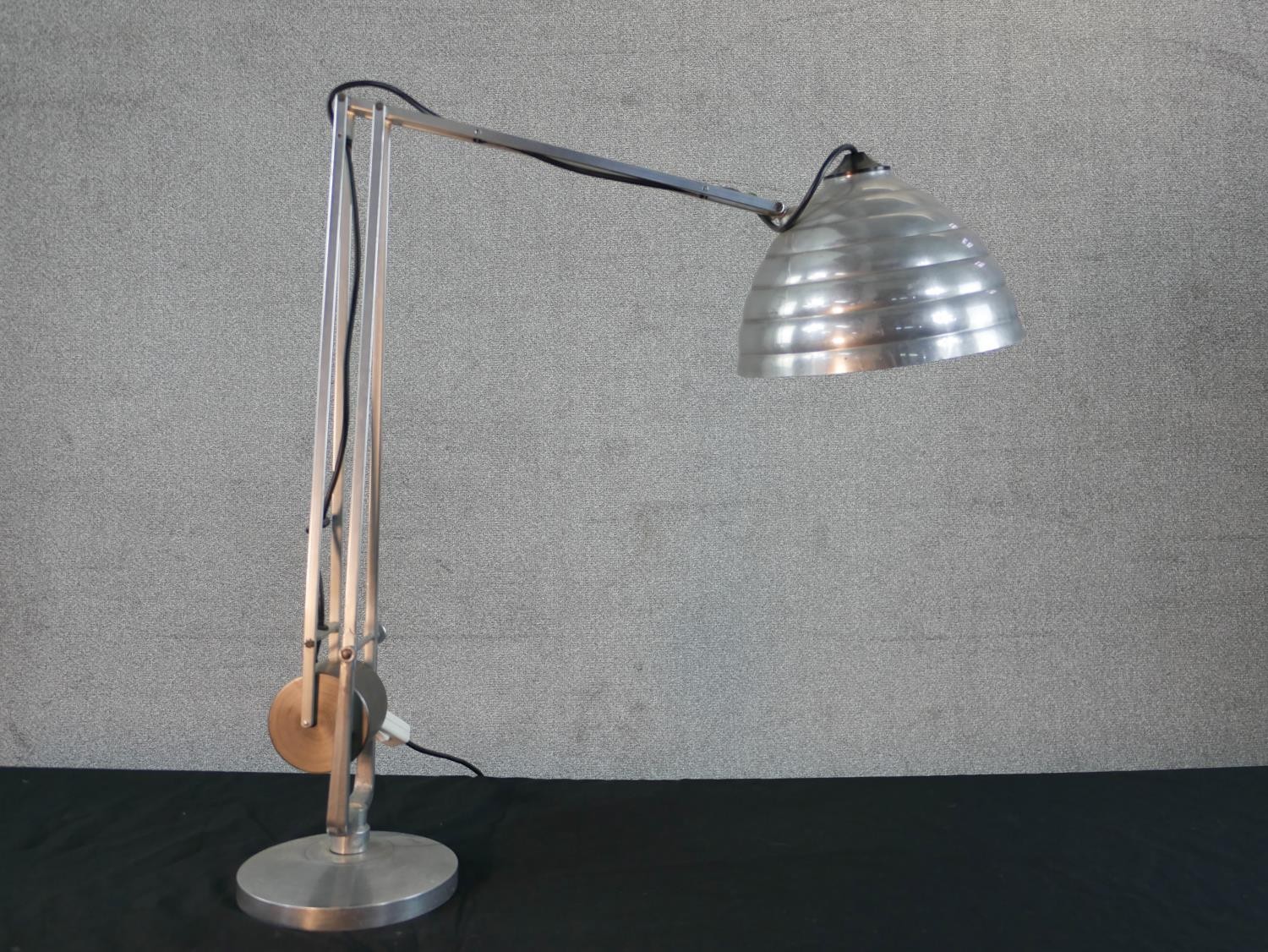 A brushed steel electric desk top angle poise style lamp, on circular foot. H.67 W.58cm