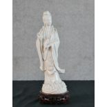 A Chinese Blanc de Chine porcelain figure of Guanyin, inscribed '65' to the underside, on a carved