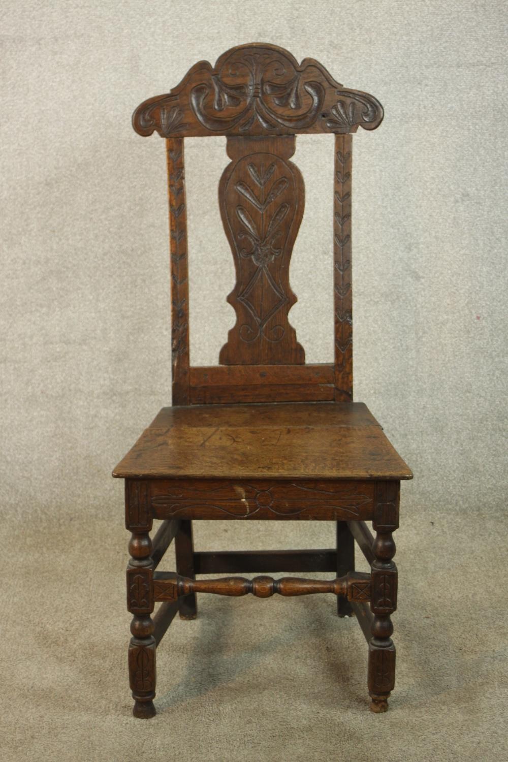 A 19th / early 20th century carved oak hall chair, with carved rail and splat back raised on