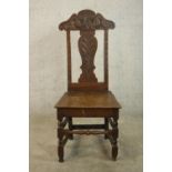 A 19th / early 20th century carved oak hall chair, with carved rail and splat back raised on