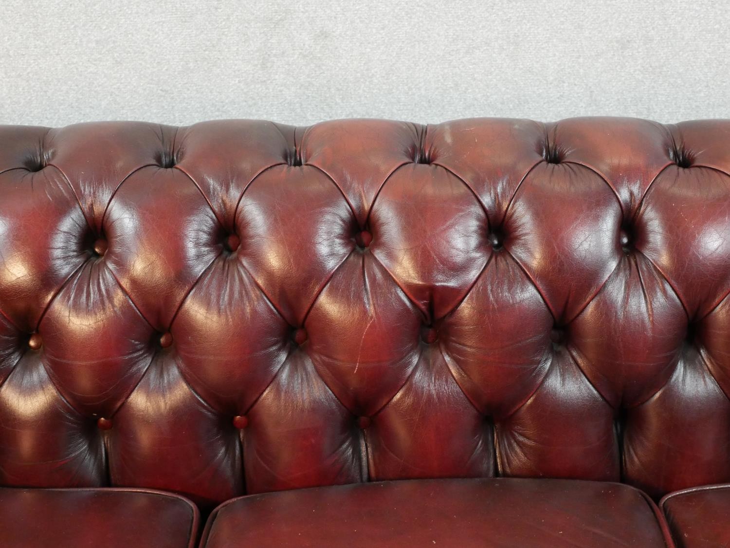 A 20th century oxblood red Chesterfield three seater settee, raised on casters, H.65 W.195 D.67cm - Image 4 of 5