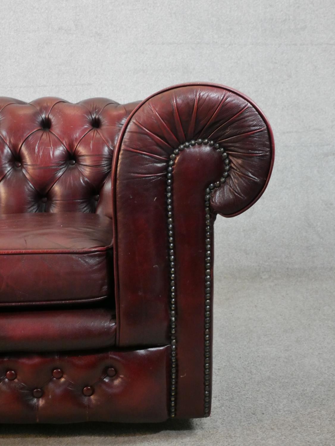 A 20th century oxblood red Chesterfield three seater settee, raised on casters, H.65 W.195 D.67cm - Image 2 of 5