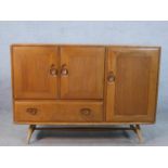 A mid 20th century Ercol beech and elm sideboard, with two cupboard doors above single drawer and