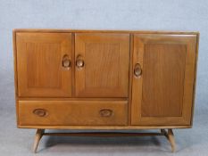 A mid 20th century Ercol beech and elm sideboard, with two cupboard doors above single drawer and