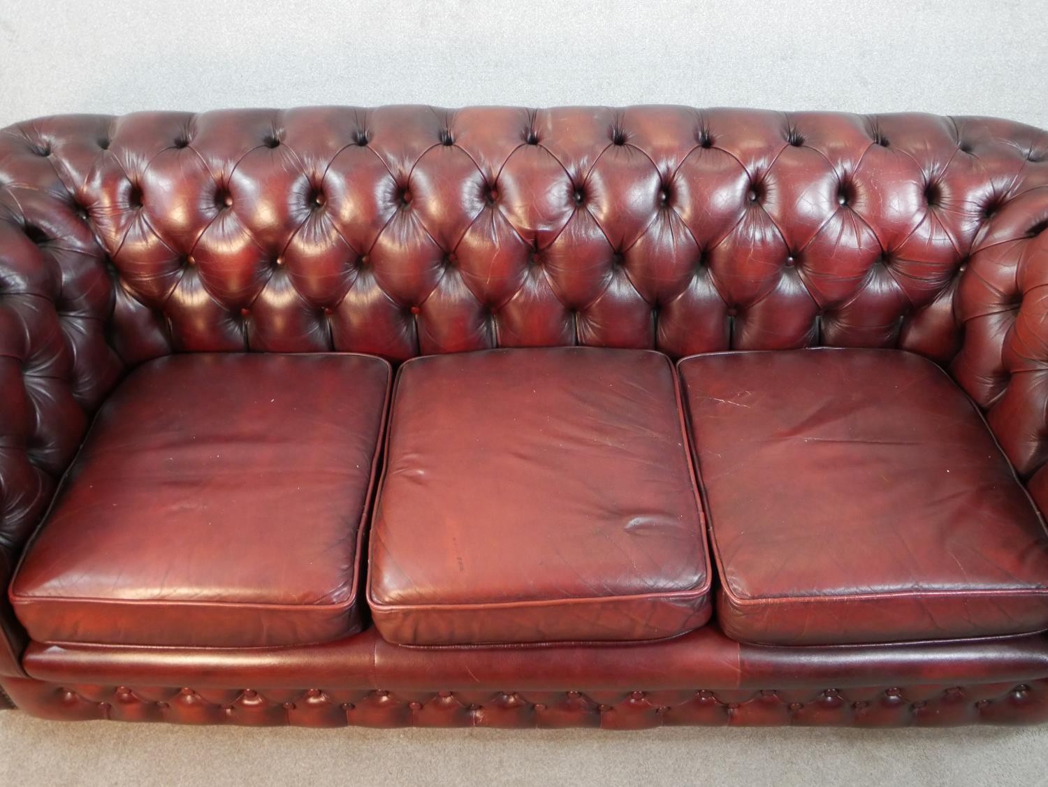 A 20th century oxblood red Chesterfield three seater settee, raised on casters, H.65 W.195 D.67cm - Image 3 of 5