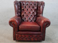 A 20th century oxblood leather Chesterfield style wingback arm chair raised on casters.
