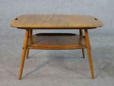 A 20th century blonde elm and beech Ercol two tier occasional tray table, model number 457, raised