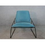 A contempory black painted metal framed Ikea lounge chair with blue upholstered cushions.