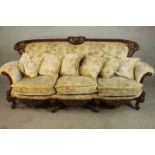 A late 20th century carved and lacquered three seater sofa, upholstered in cream coloured foliate